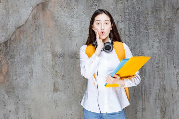 Female student with backpack and headphones looking shocked. High quality photo