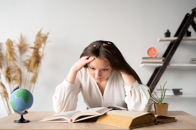 Female student with headache and fatigue sits at the table and studies mathematics with textbook An unmotivated teenager solves his study problem Difficulty concentrating Place for your text