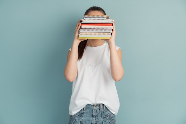 Female student with a mountain of notebooks and books in her hands