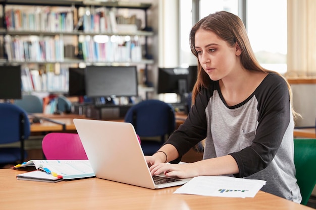 Female Student Working At Laptop In College Library