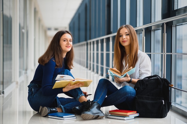 Female students sitting on the floor and reading notes before exam