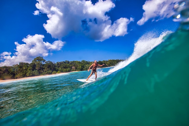 Foto surfista femminile su un'onda blu al giorno pieno di sole