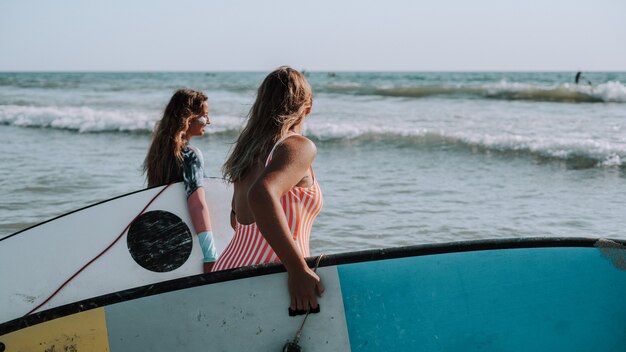 Female surfers holding their surfboards and walking to the sea