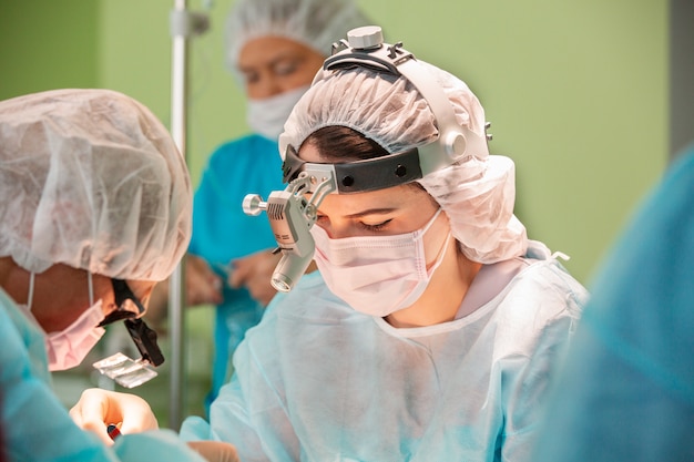 Female surgeon doctor or intern wearing protective mask and hat.