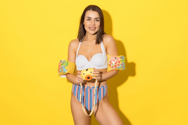 A female swimming instructor on a yellow background a model in a swimsuit inflatable sleeves