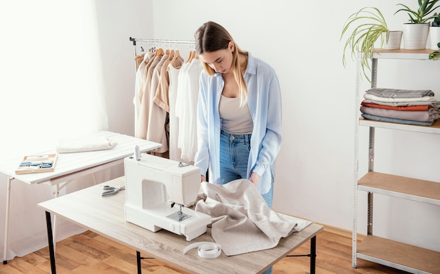 Photo female tailor using sewing machine in the studio