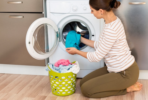Photo female taking clothes out washing machine