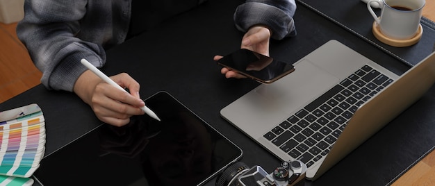 Female taking note on digital tablet while looking information on smartphone