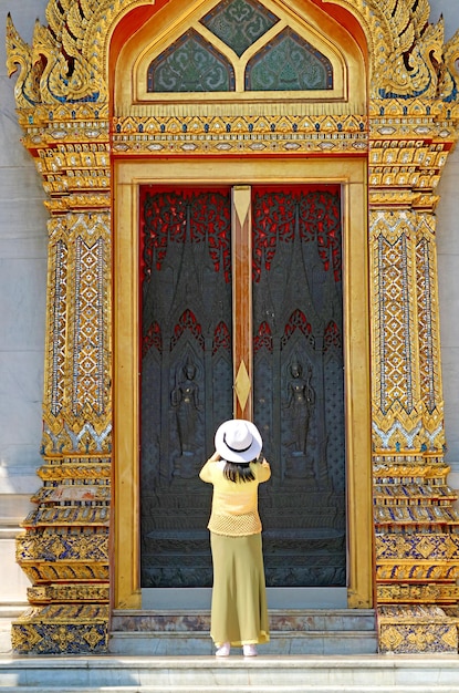 Female taking photo of ordination hall door  of wat benchamabophit marble temple bangkok thailand