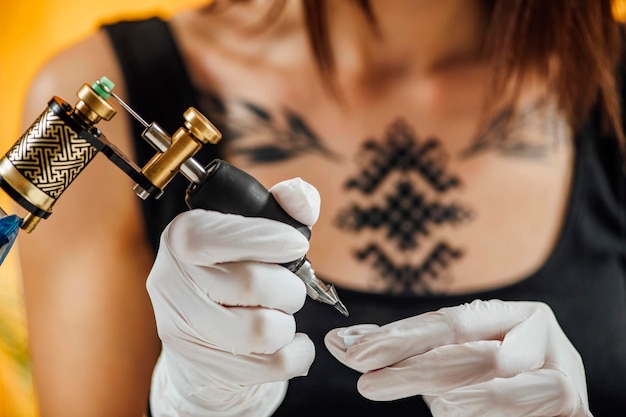 Female Tattoo Artist Prepares Tattoo Machine for Making a Tattoo on a Men's Arm