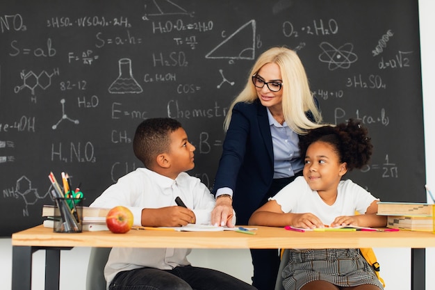 A female teacher helps school children solve problems at school International team Back to school