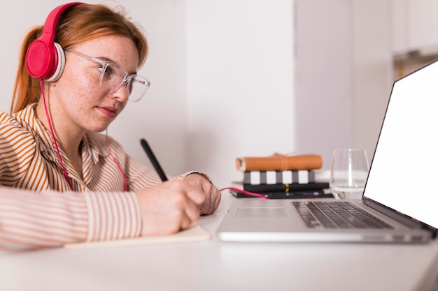 Insegnante femminile a casa in possesso di un corso online utilizzando laptop