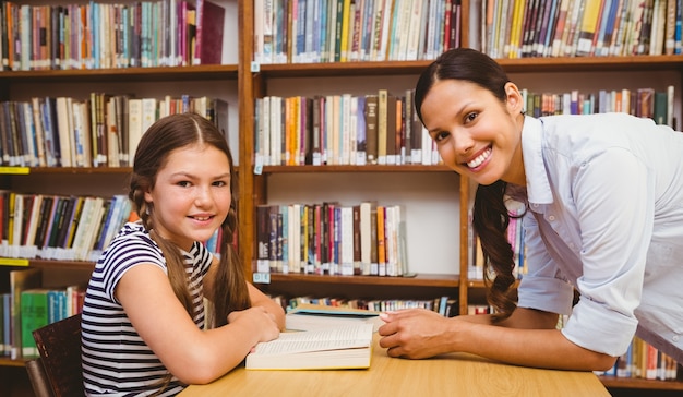 Female teacher and little girl in library