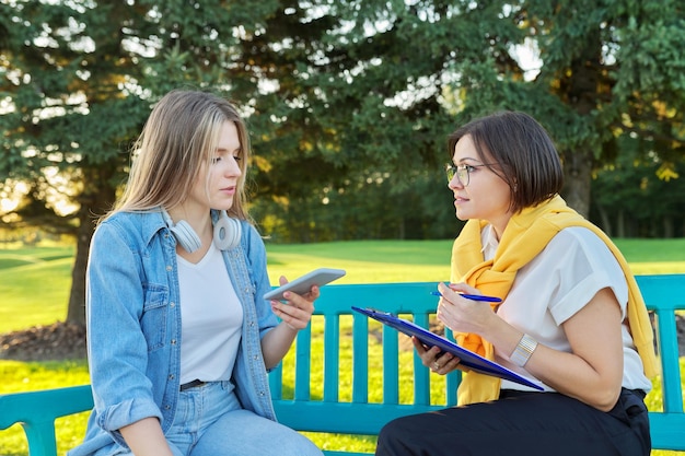 Female teacher meeting with student young woman outdoors