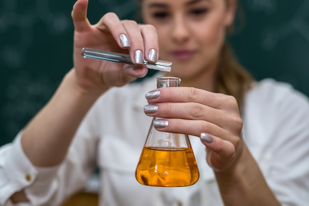 화학 수업 중 함께 멀티 컬러 화학 액체를 혼합하는 여성 교사. 과학적