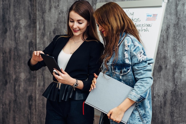 Female teacher and student looking at screen of tablet PC using application