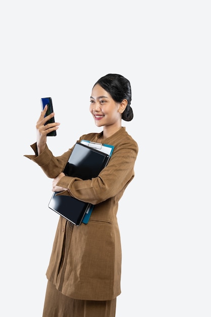 Female teacher in uniform makes a call using phone while carrying laptop