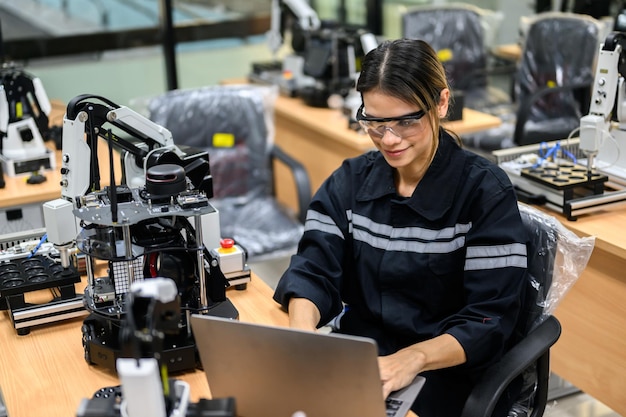 Photo female technician engineer using laptop checking and operating automatic robotic machine