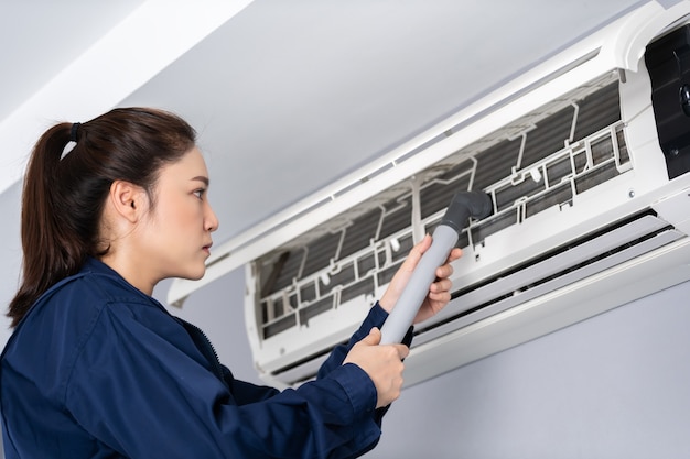 Photo female technician service using vacuum cleaner to cleaning the air conditioner