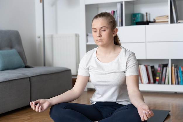 Female teenager meditating at home Young woman making breathing exercise