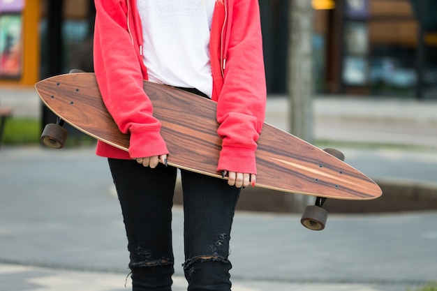 Female teenager posing with skateboard or long board\
outdoors.