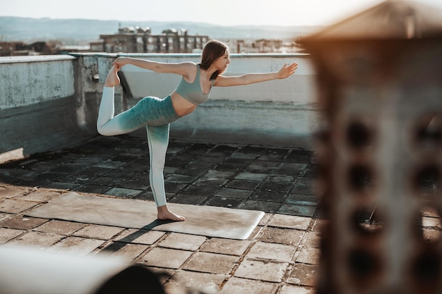 Female teenager practicing yoga on a rooftop terrace.