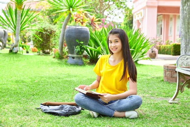 Female teenager reading book in park