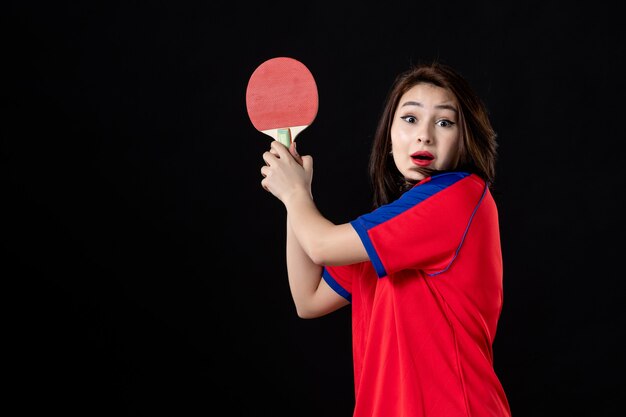 Female tennis player with racket on black