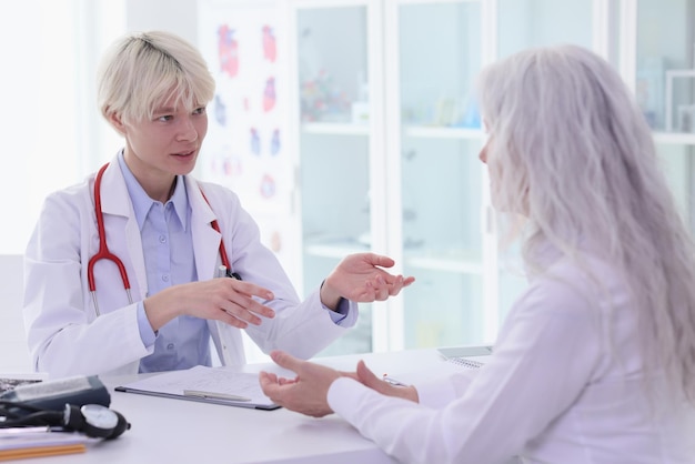 Female therapist consults mature patient during appointment in hospital office doctor talks to