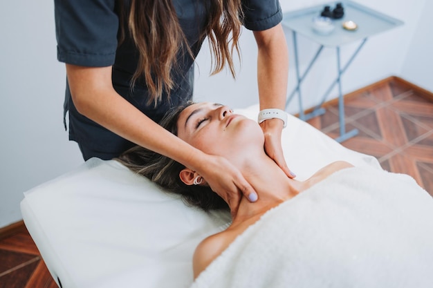 Female therapist making a neck massage to a face up female patient Wellness center spa Skin care