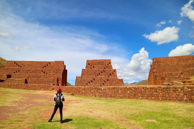 Turista femminile ammirando le antiche strutture di rumicolca, incredibile sito archeologico della civiltà wari nella regione di cusco, perù