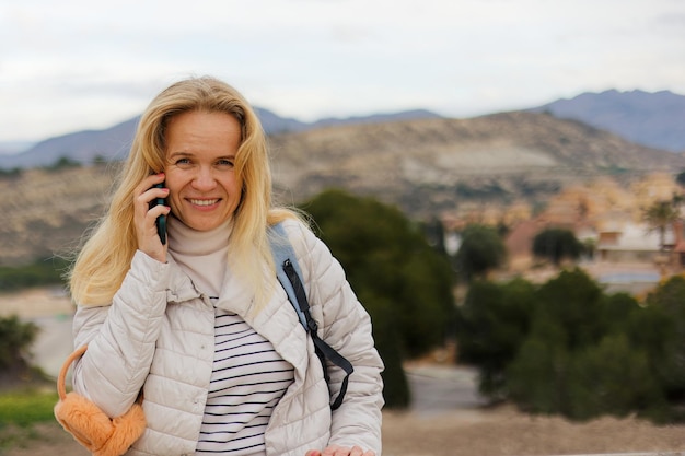 A female tourist communicates on a mobile phone against the background of the city