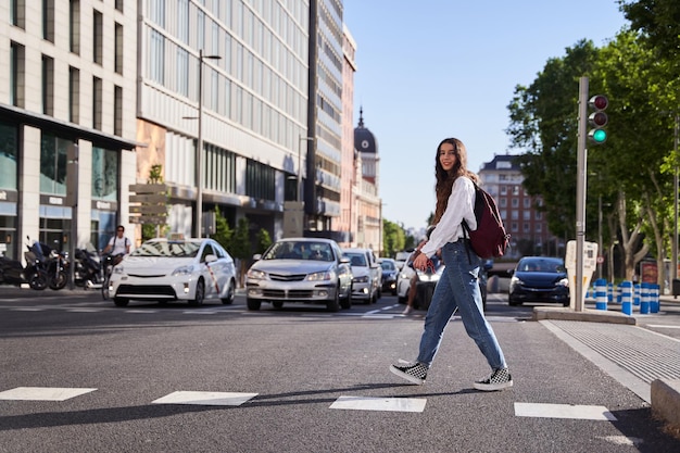 Female tourist crossing a crosswalk in Madrid young Caucasian woman at sunset