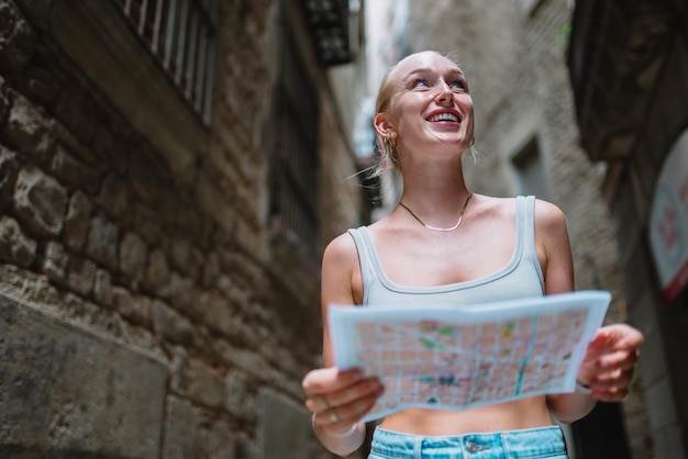 Female tourist maps user walking in old town alley an using a map Barcelona Spain