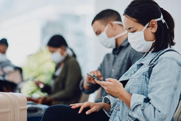 Female tourist on phone traveling during covid at airport waiting for departure wearing a mask for protection For hygiene and healthcare security follow corona virus social distance regulations