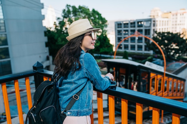 female tourist putting hands on the handrail and seeing the city view. travel in los angeles activities. USA summer destination.