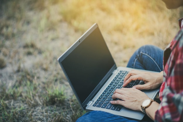 Female tourist sitting on grass looking at computer looking for directions to tourist attractions