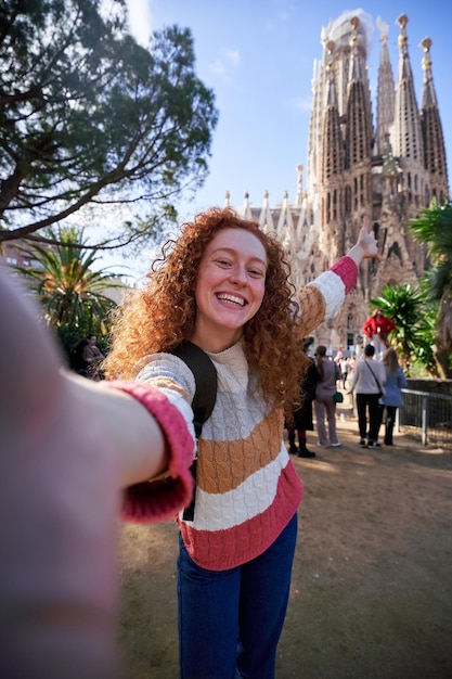 female tourist taking a happy selfie with sagrada familia in barcelona spain