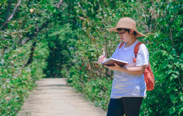 Female tourist taking notes on walkway while ecotourism in\
mangrove forest at natural parkland