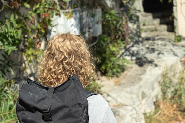 Female tourist walking in sunny weather Copy space near woman back view Girl traveller with backpack