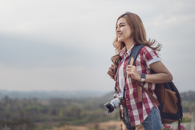 Female tourist with backpack and camera in countryside