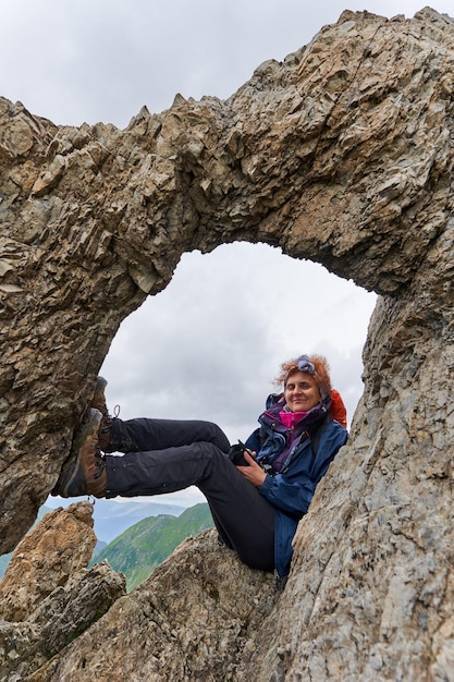 Female tourist with backpack hiking on a trail in the\
mountains