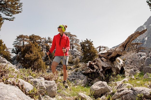 Female tourist with hiking equipment among rocks