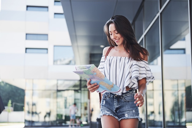 Female tourist with map visiting a new city and is looking for a way to the hotel.