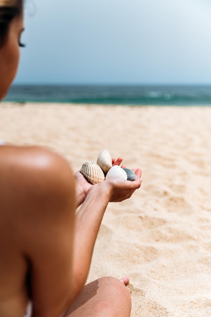 Female tourist with seashells on seashore