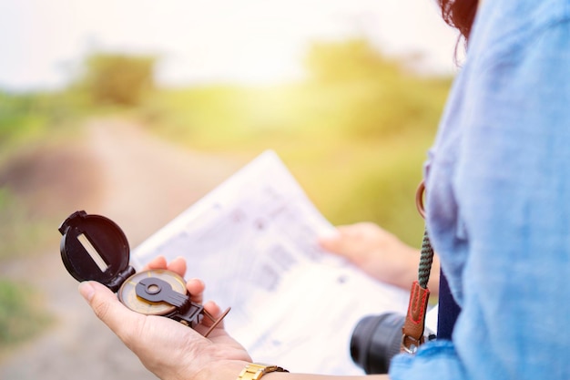 Female tourists are using a compass and map to find the direction of a place