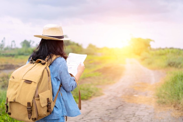 Female tourists are using a map to find the direction of a\
place the road is a long way an adventure trip by yourself with a\
backpack in the back