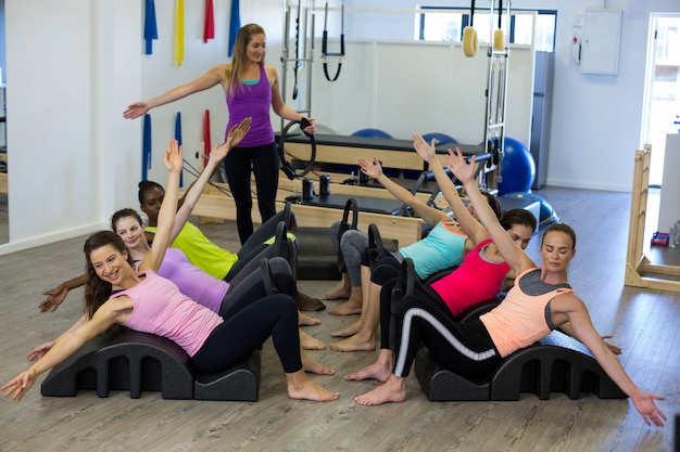 Allenatore femminile che assiste un gruppo di donne con esercizio di stretching sulla canna dell'arco