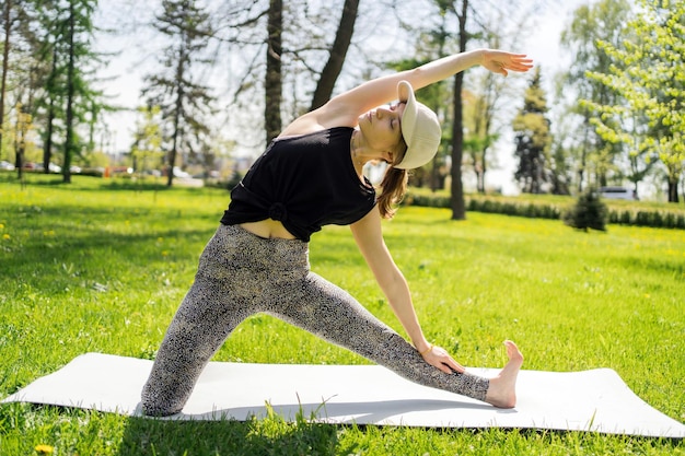 A female trainer does a yoga asana pose workout in the park harmony and balance of the body