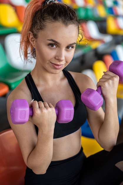 Female trainer doing exercises with dumbbells on stadium chairs active lifestyle